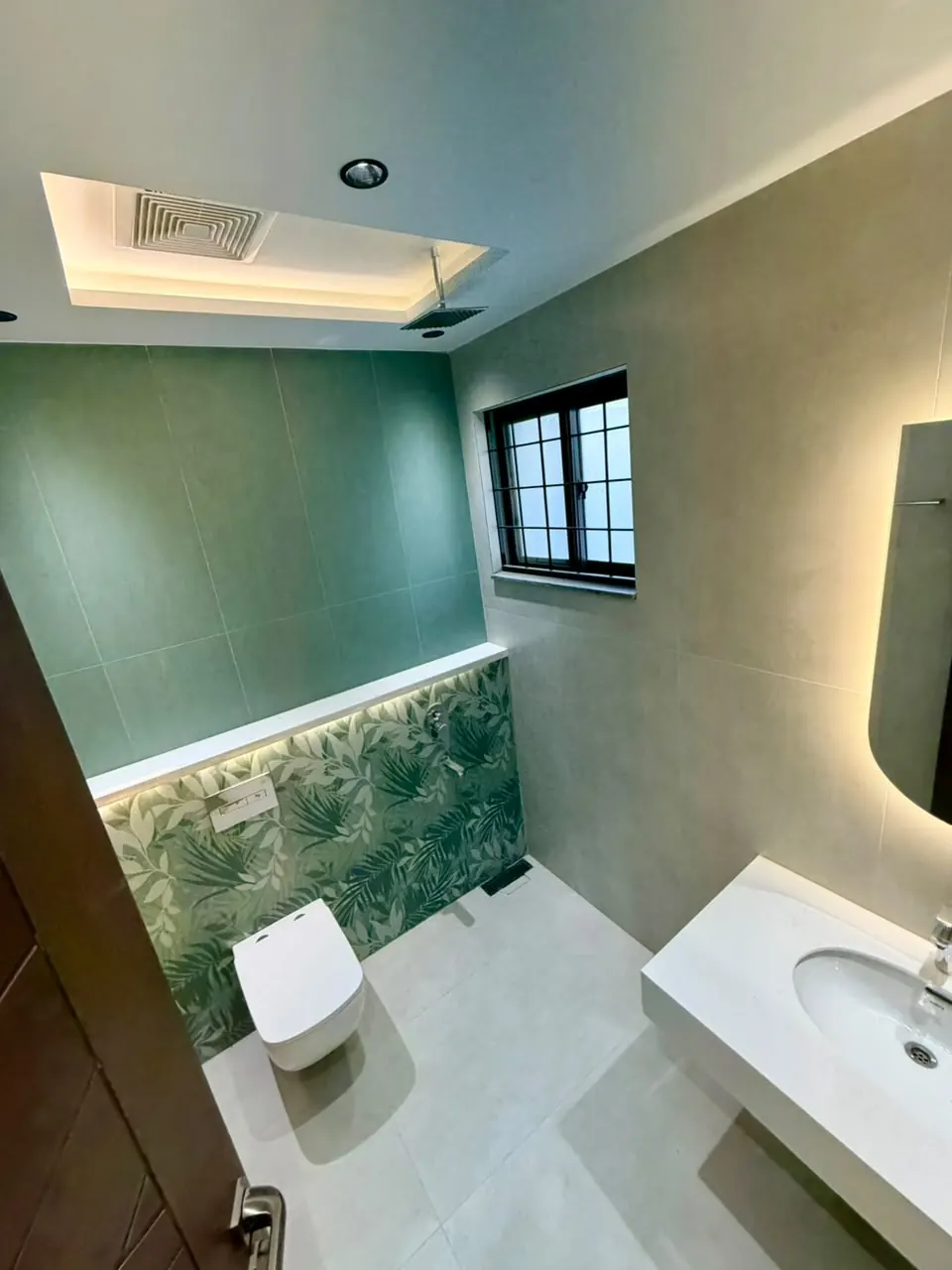 Bathroom with green tiles and botanical wall